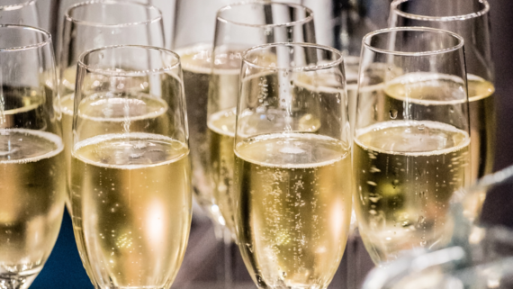 Close-up of multiple champagne flutes filled with sparkling champagne. The glasses are arranged in rows, showcasing the golden bubbly liquid with rising bubbles, creating an elegant and festive atmosphere.