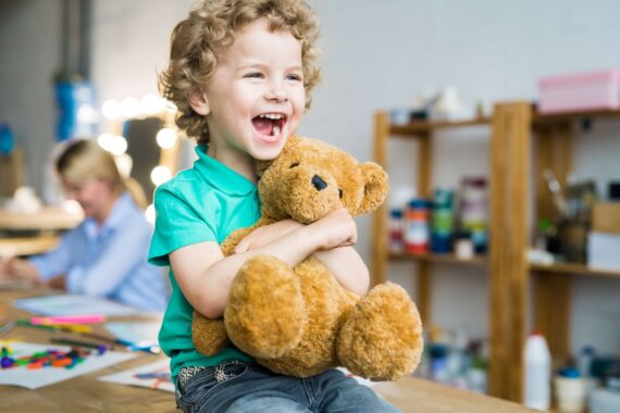 A child smiles after being gifted a teddy bear.